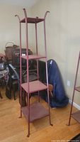 Full view of red tone cast iron stand showing the three shelves and curved accents at the top
