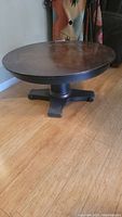 Full view of round coffee table showing copper patina top and black pedestal base on wood floor
