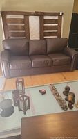 Front view of brown leather couch with three cushions and Velcro.