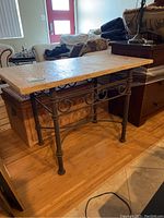 Full view of rectangular outdoor table showing treated stone top and metal base with decorative scrollwork detail on the sides.