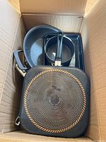 Top down view of cookware in cardboard box showing frying pans, saucepan, and roasting pan