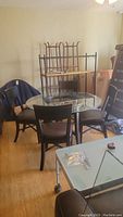 Round glass top table with dark wood base and four chairs with leather seats seen from an angle with shelving in background.
