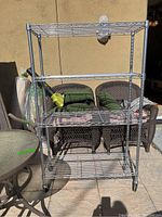 Front view of the metal wire rack with four wire shelves and caster wheels, showing the overall frame and structure.