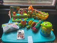 Wide shot showing entire assortment of animal-themed children's toys on blue plastic tray including tractor, shape sorter, caterpillar pull toy, and other animal toys.