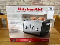 Front of box featuring image of the stainless steel 4-slice toaster with two slices of bread toasted, and key features listed like bagel button and wide slot.