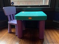 Green plastic child table with purple legs, viewed from front and slight side angle showing table and chair.