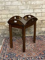 View of the table with leaves folded up displaying cutout handles and brass hinges on top.