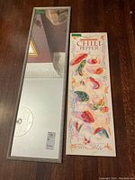 Photo showing both rectangular framed mirror and chili pepper art print side by side on a wooden floor.
