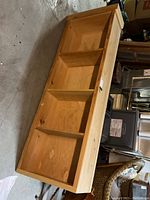 Shelving unit laid horizontally showing three fixed interior shelves dividing space into four compartments. Natural pine wood with visible knots and grain.