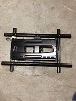 Top view of black metal TV wall mount showing horizontal bars and mounting bracket.