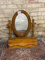Front view of vintage pine vanity swing mirror showing oval mirror and pine wood base with hinged storage box lid.