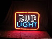 Lit Bud Light neon sign showing red border, white 'BUD' lettering, and blue 'LIGHT' lettering on black background.