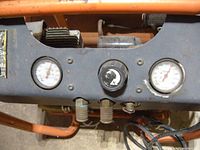 Close up of the control panel showing two pressure gauges and a regulator knob with adjustment markings.