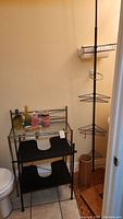 View of bathroom storage items including tension shower caddy and two shelving units against wall