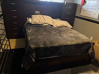 Full frontal view of the queen bed frame showing the headboard with built-in side cabinets and mattress area with bedding.