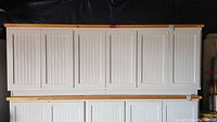 Front view of large white cabinet with six beadboard paneled doors and natural pine top and base trim.