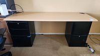 Full view of the desk with wooden top and two black metal filing cabinets as legs.