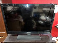 Front view of the 31 inch black Emerson flat screen TV on its stand