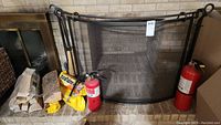 Wide view of fireplace screen, firewood, tools, and fire extinguishers
