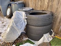 Four stacked Michelin Latitude Tour mud and snow tires with tread visible and plastic cover on one tire.