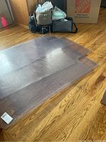 Four clear plastic desk chair mats on hardwood floor with visible anti-slip dots and rounded corners.