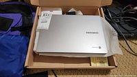 Samsung Chromebook laptop closed in box showing silver lid with Samsung and Chrome logo