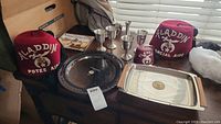 Full lot showing two red Shriners fezzes with embroidery, one silver ornate tray, one metal rectangular tray with wooden handles, and six small silver goblets.
