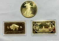 Three 1 oz gold clad items: two bars and one round coin, placed on white background.