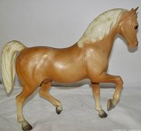 Side view of vintage prancing palomino stallion plastic horse figurine highlighting its pose and coloration