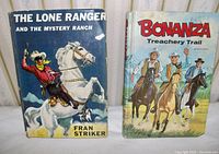Photo showing two vintage classic books, 'The Lone Ranger and the Mystery Ranch' and 'Bonanza - Treachery Trail' with colorful illustrated covers in good condition.