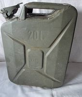 Front view of a vintage olive drab metal jerry can with '20L' and 'FAW1' embossed markings, showing the clasp lid and handle.
