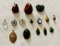 Photo showing entire assortment of 15 vintage gemstone charms and pendants arranged on white fabric.
