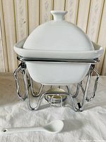 Front view of ceramic dish on metal stand with lid and spoon