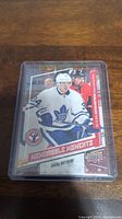 Front of Auston Matthews rookie card from 2016-17 Upper Deck 'Memorable Moments' series in a protective plastic case showing player in Toronto Maple Leafs uniform.