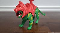 Front angle view of green and yellow Battle Cat with red battle armor and saddle.