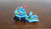 Side view of blue Battle Ram toy vehicle showing wheels and red turret