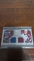 Photo of dual jersey card featuring Joe Sakic and Brad Richardson in Colorado Avalanche jerseys, protected in a clear sleeve, showing front design and fabric swatches.