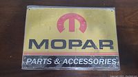 Photo of Mopar metal sign with yellow background and logo