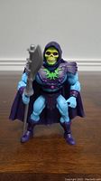 Front view of Skeletor action figure holding mace showing detailed facial sculpt, torso armor and cape.