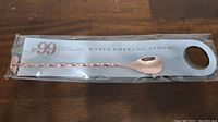 Cocktail spoon sealed in packaging with visible branding and twisted handle design.