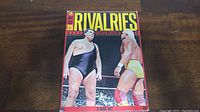 Front cover of WWE Top 25 Rivalries In Wrestling History DVD set featuring two wrestlers facing off, one in black singlet and the other in yellow trunks.