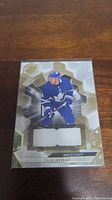 Front image of Zach Hyman Maple Leafs hockey card with visible embedded jersey swatch in white fabric.