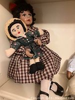 Photo of handcrafted Tammy porcelain doll wearing a red-brown plaid dress, holding a small cloth doll with straw hat.