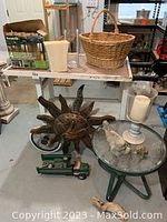Full lot showing metal sun wall art, green metal table with glass top, vases, basket, candle holder, toy truck, and box of solar light.