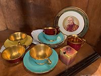 Overview of all cups, saucers and sugar pot on wood surface