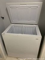Front view of the white chest freezer with lid open showing divided interior with two removable wire baskets.