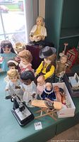 Photo showing a group of vintage dolls in various outfits and two miniature sewing machines.