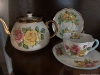 Photo showing the Gibson Staffordshire teapot with large pink and yellow roses, gold-trimmed lid and handle, alongside the Shelley teacup and matching saucer with pink and yellow flowers.
