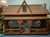 Front exterior view of the wooden miniature log cabin on spinning stand with porch and hanging planters