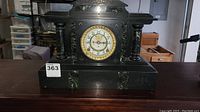 Front view of black slate mantel clock with green marble columns, brass bezel and enamel dial